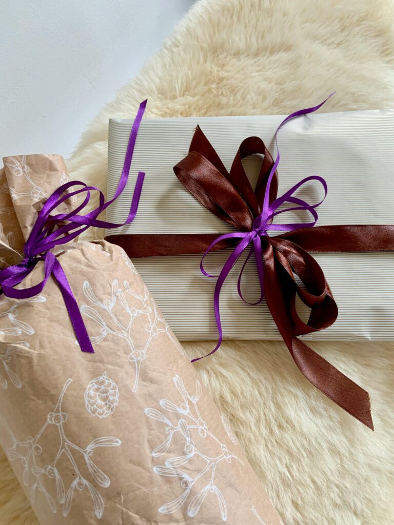 Elegant gift packages wrapped with purple and brown ribbons on a fluffy surface, ideal for Christmas or special occasions.